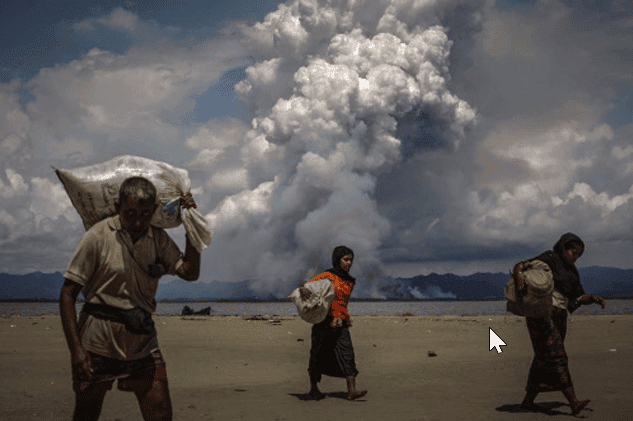 Smoke is seen on the Myanmar border as Rohingya refugees walk on the shore after crossing the Bangladesh-Myanmar border by boat (Part of Reuters series that won Pulitzer for feature photography)