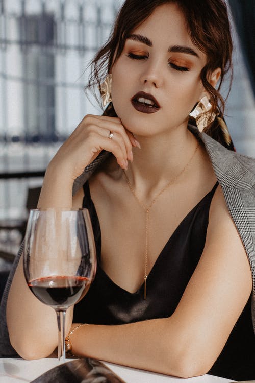 Alluring young lady chilling in restaurant with wineglass